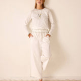 Women's travel-friendly white long-sleeve relaxed fit cotton knit tee and matching wide-leg pants set.