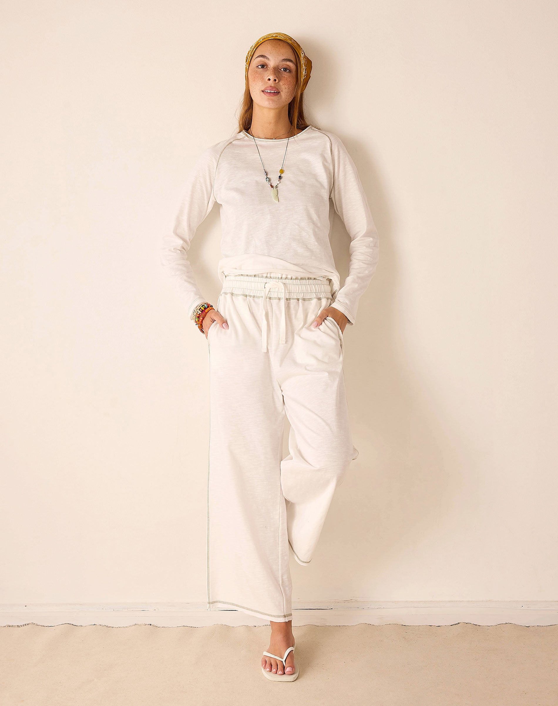 Women's travel-friendly white long-sleeve relaxed fit cotton knit tee and matching wide-leg pants set.