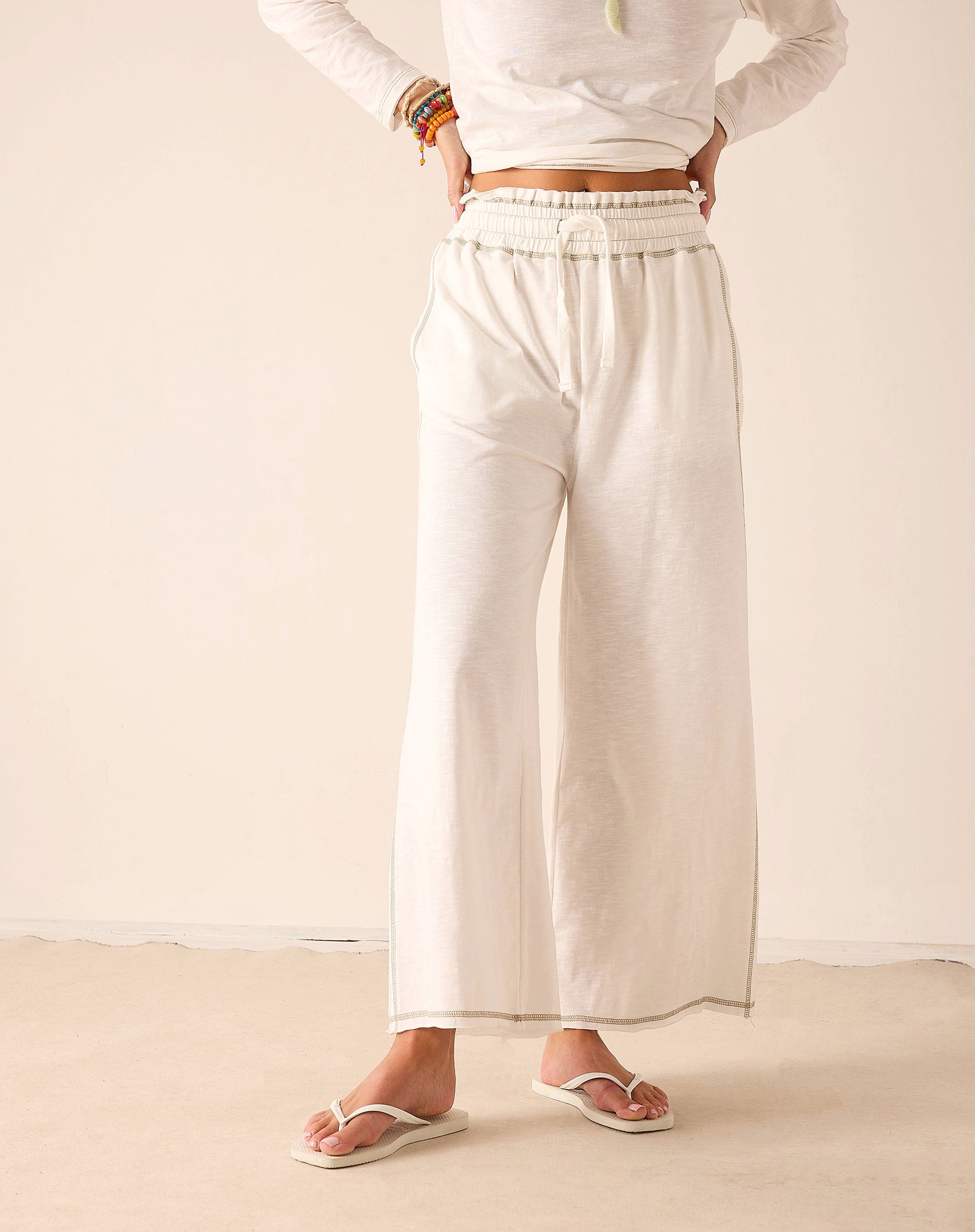 Off-white wide-leg pants in a lightweight woven fabric with an elasticated waistband and finished hems.
