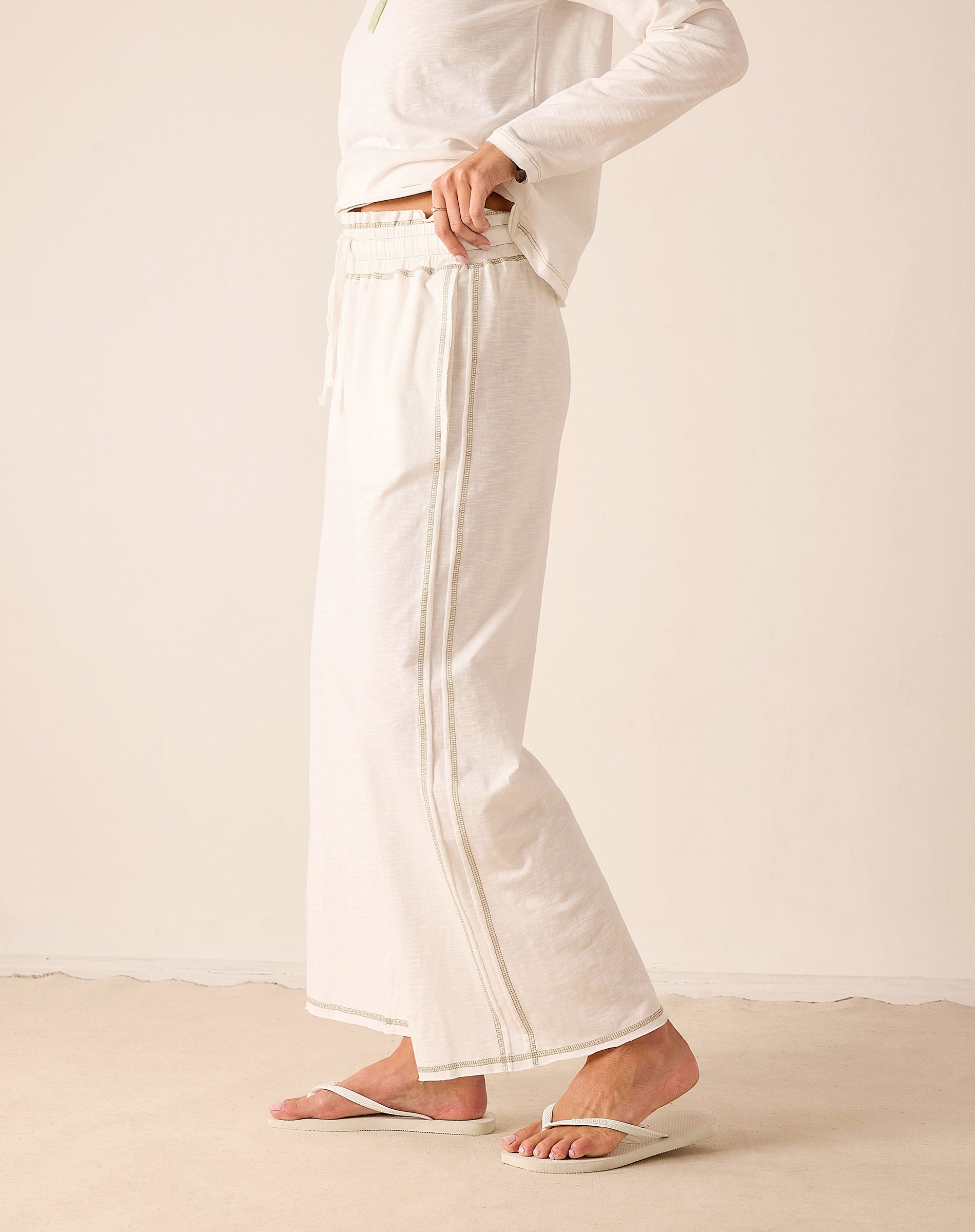 White wide-leg linen pants featuring a vertical seam detail.