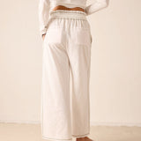 White wide-leg jersey pants with elastic waistband and side pockets.