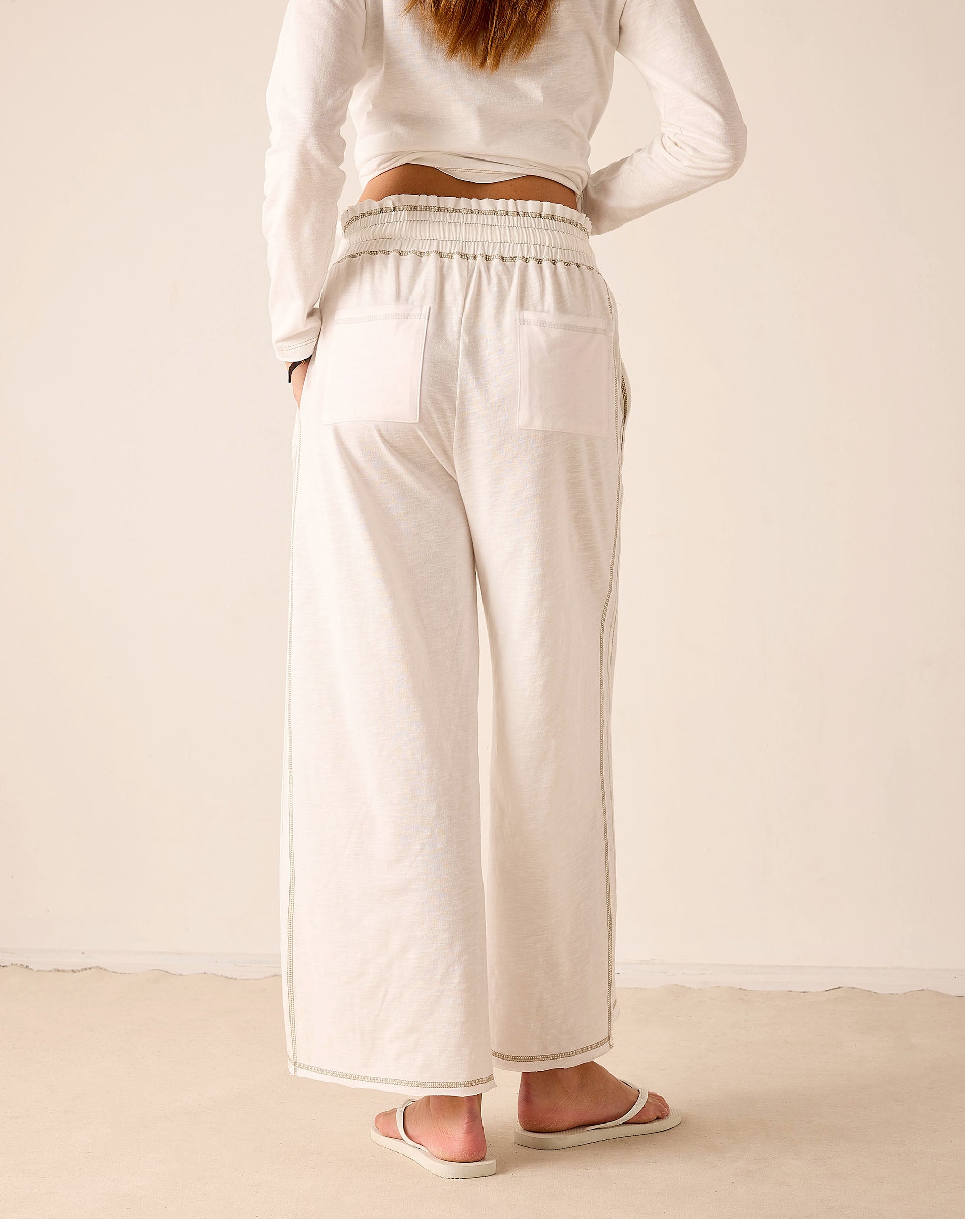 White wide-leg jersey pants with elastic waistband and side pockets.