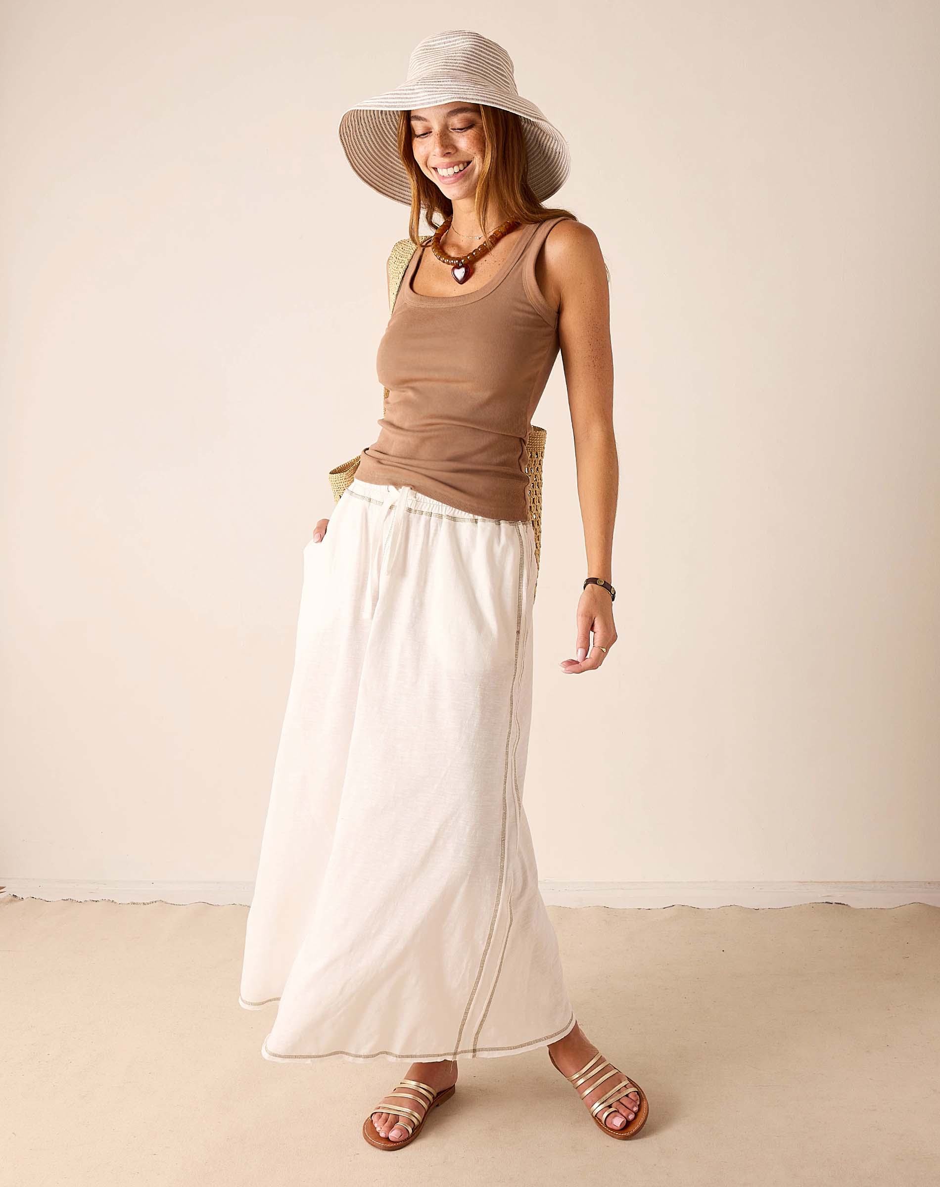 Ladies' travel-ready taupe ribbed cotton tank top paired with a white linen A-line skirt featuring a side slit.