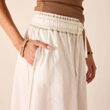 White tiered linen tee skirt with a gathered waist and drawstring detail.