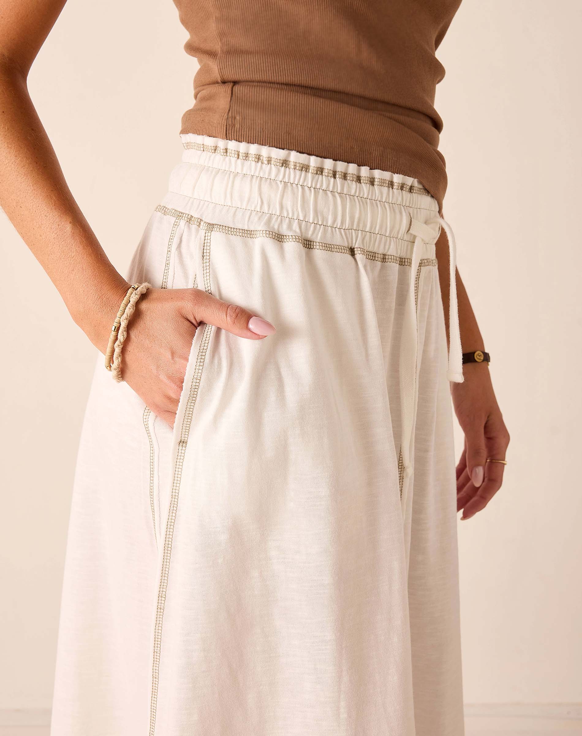 White tiered linen tee skirt with a gathered waist and drawstring detail.