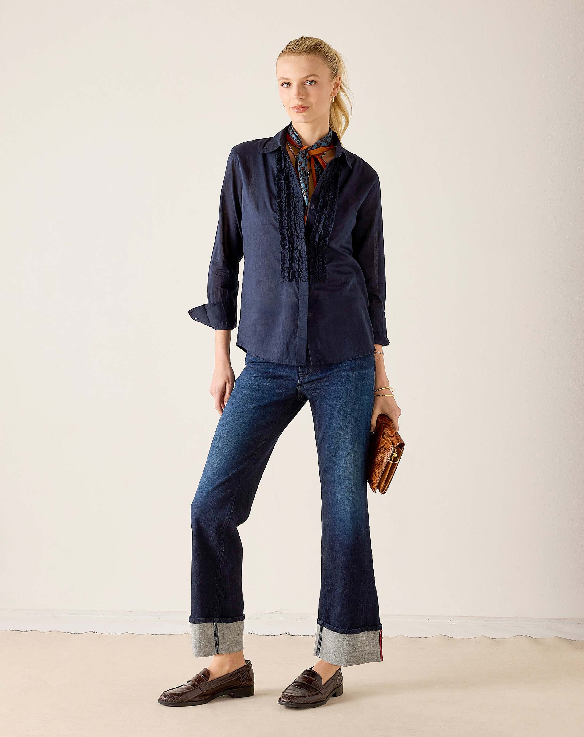 Women's travel-friendly navy blue tuxedo ruffle shirt with a button-up front and sheerer ruffled detailing on the bodice.