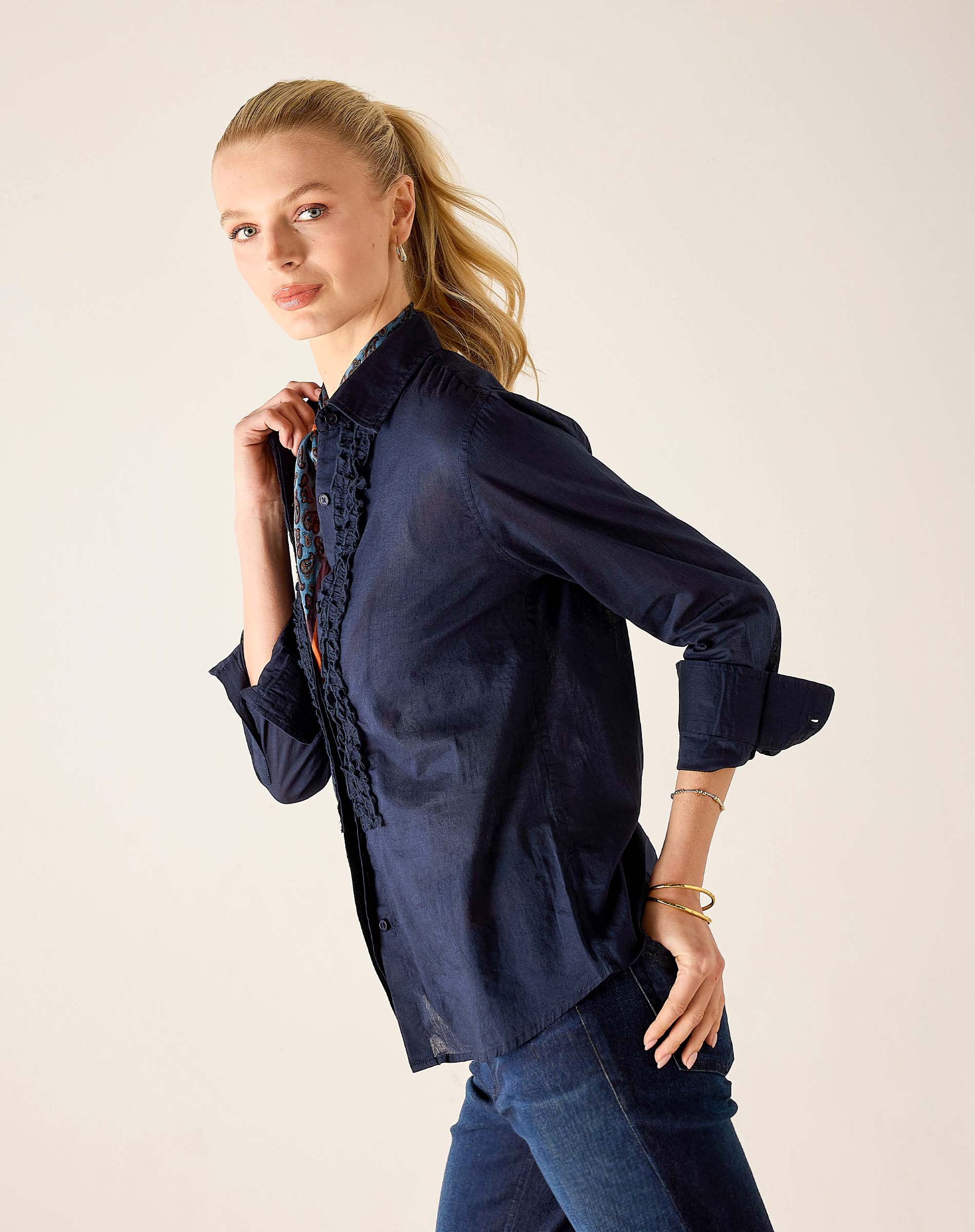 Navy silk-finish blouse featuring a tuxedo ruffle detail and buttoned cuff.