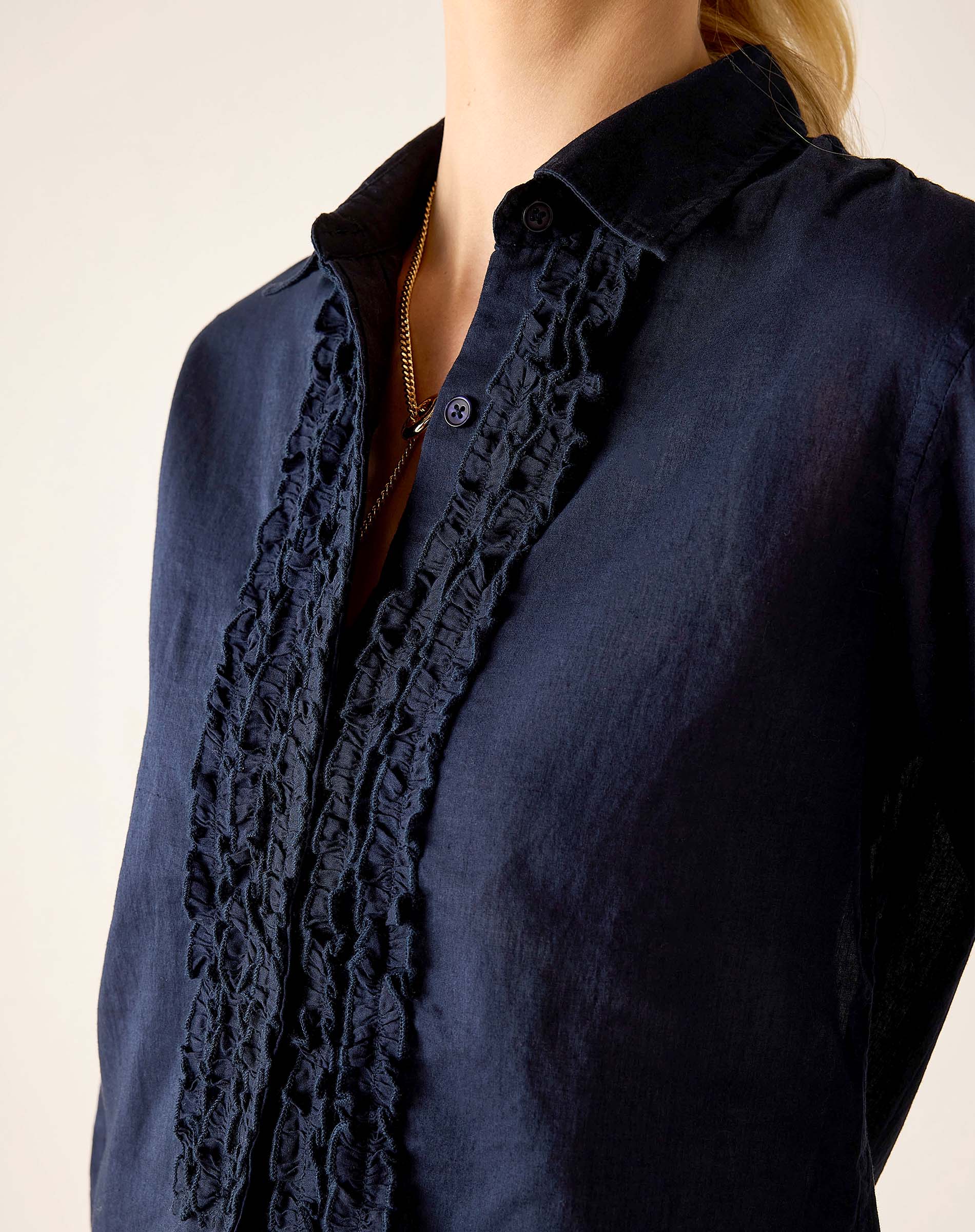 Navy blue ruffled tuxedo shirt with button front and feminine detail.