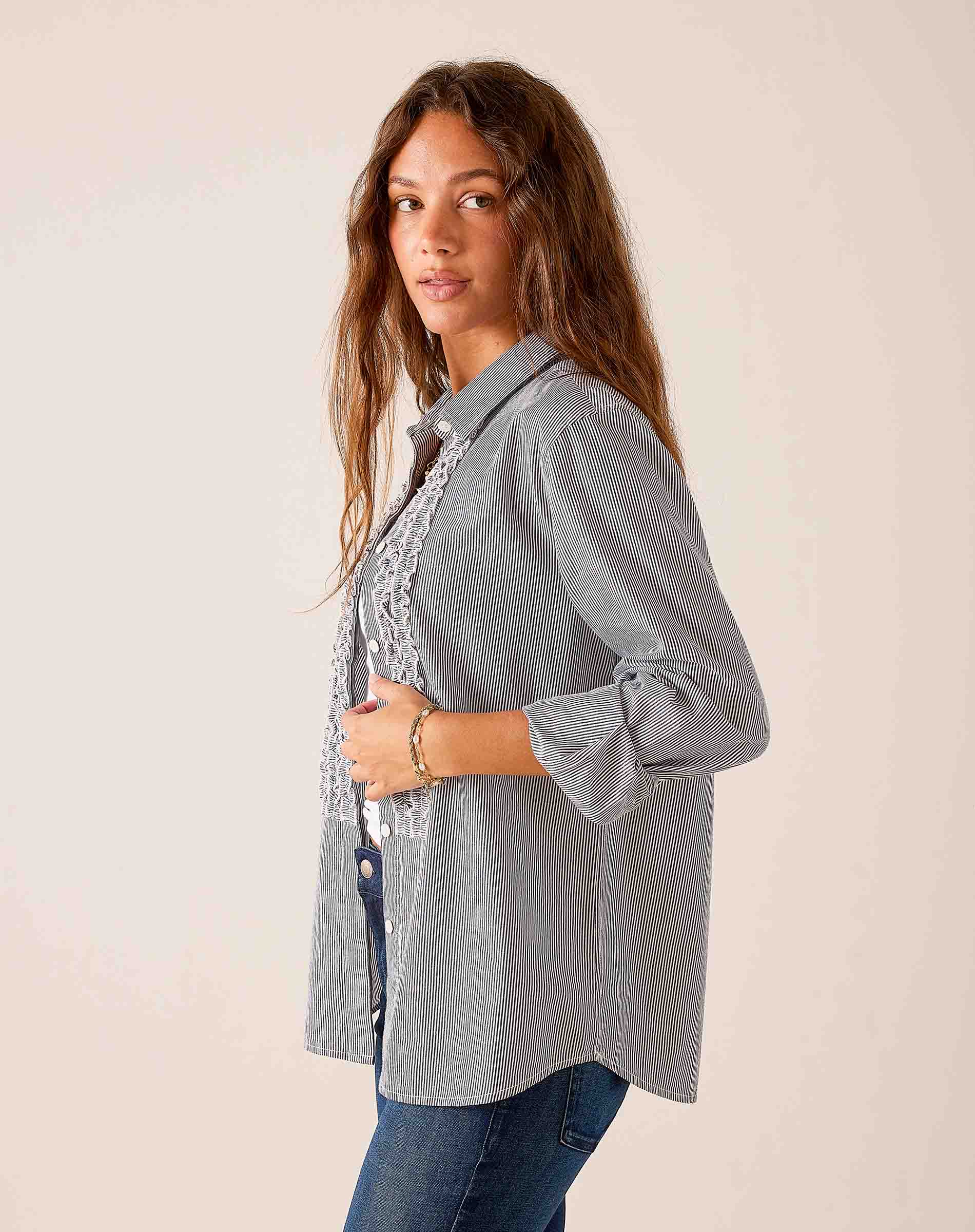 Soft black pinstriped button-down shirt featuring a feminine ruffled tuxedo front and tiered detail.