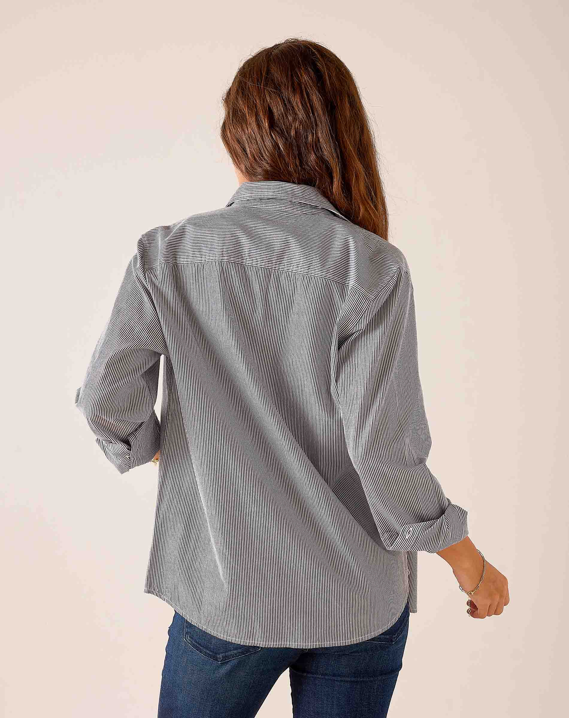 Back view of a soft black pinstripe button-down shirt featuring rolled sleeves and a relaxed fit.