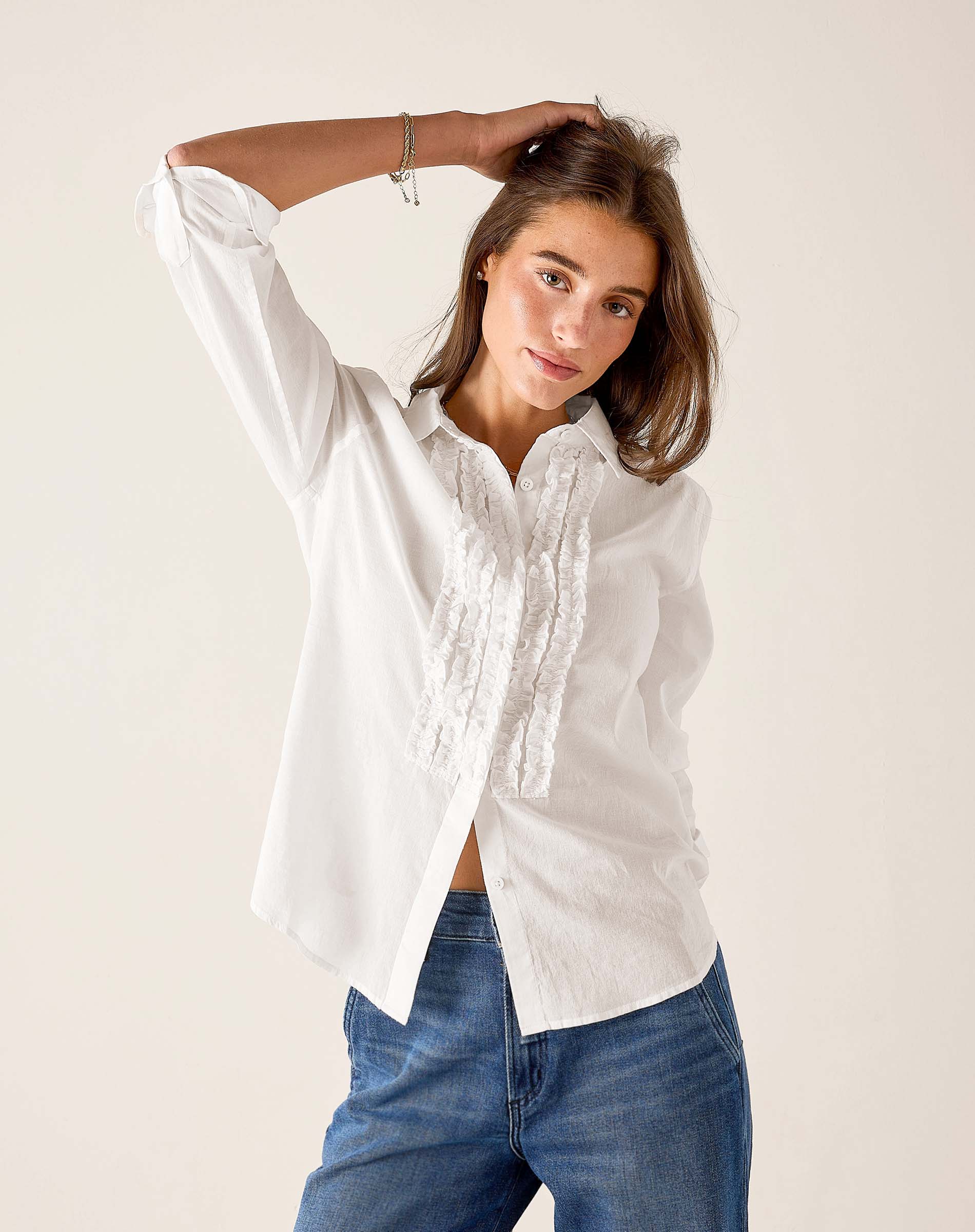 White ruffled tuxedo shirt in a crisp cotton blend featuring feminine ruffle details and button front.