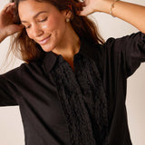 Women's travel-friendly black ruffled tuxedo top with button front and textured detail.