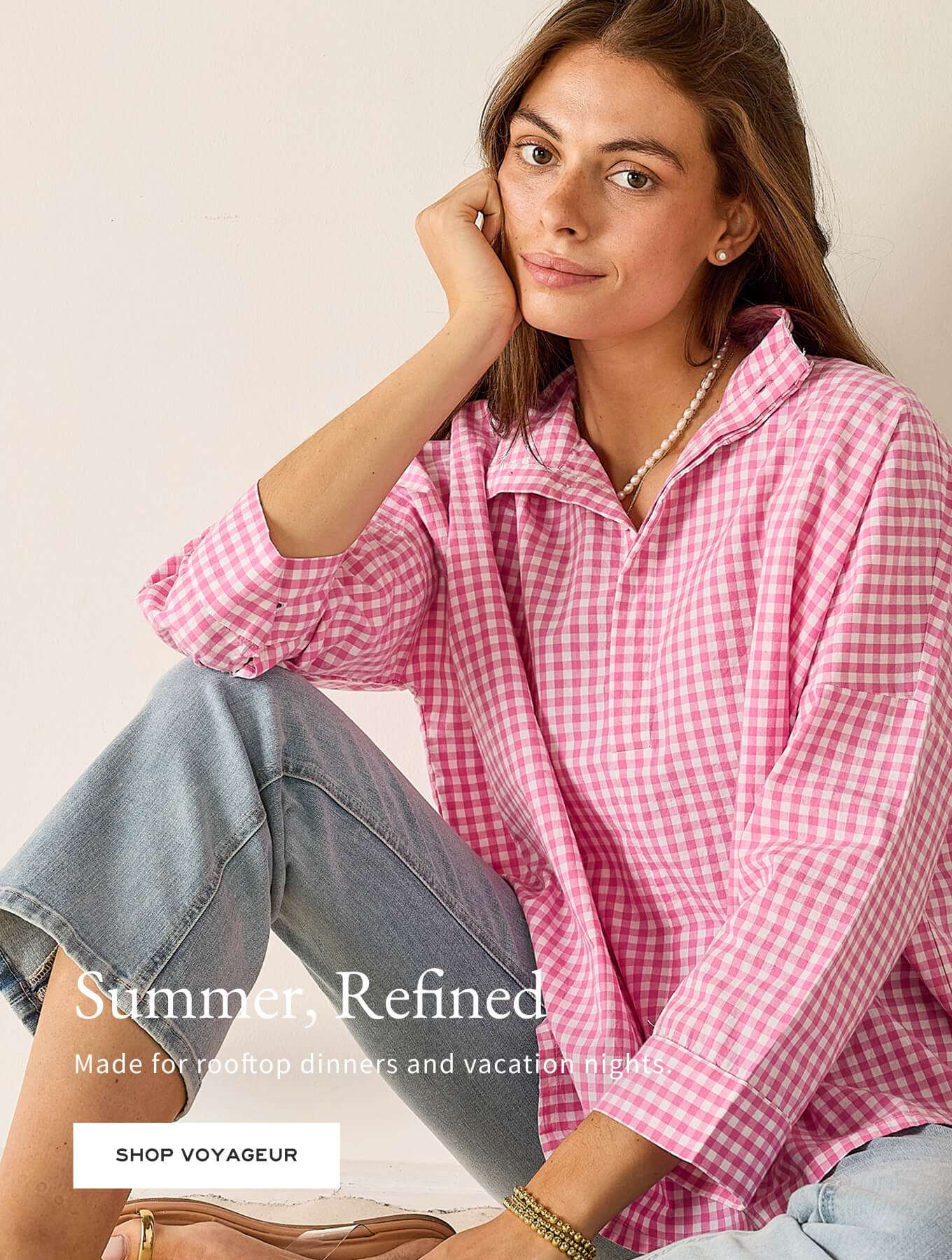 Woman wearing a pink checkered shirt and jeans sitting on a couch with text overlay.
