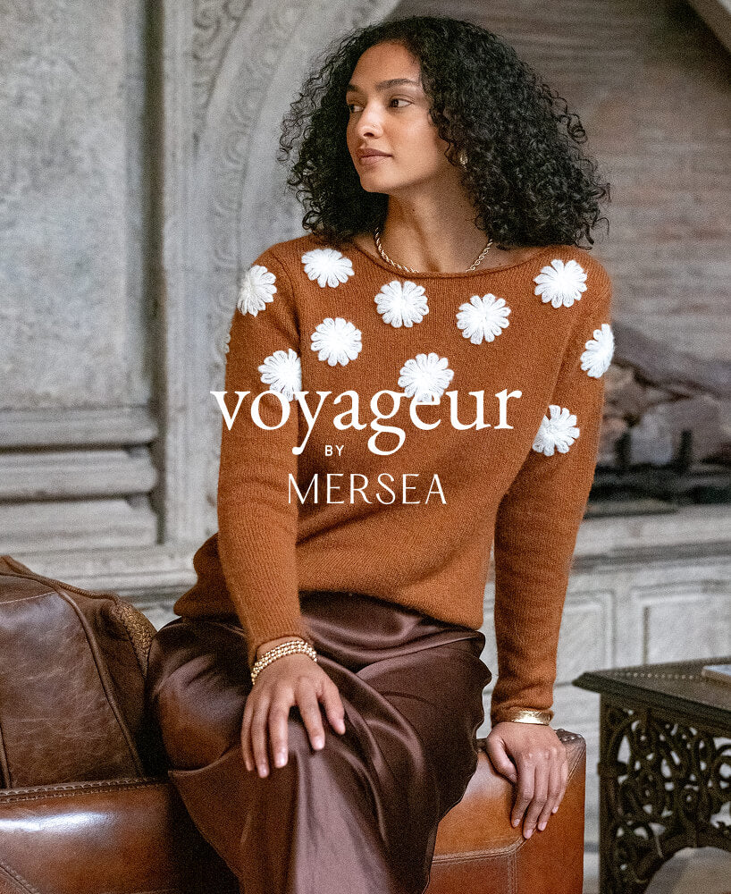 Woman wearing a brown sweater with white floral patterns, sitting on a leather chair.