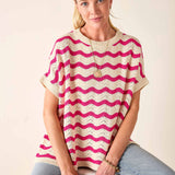 Woman wearing a pink and white striped sweater against a plain background