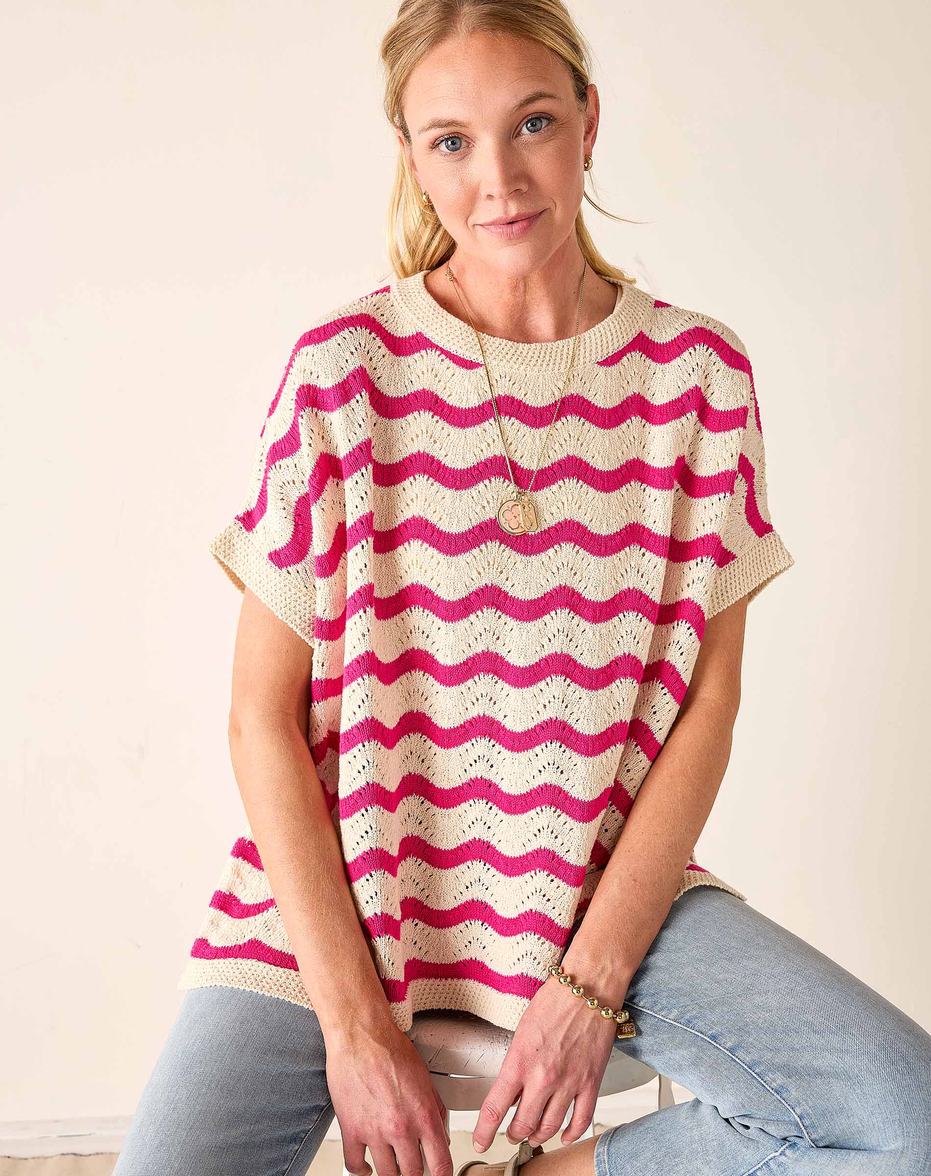Woman wearing a pink and white striped sweater against a plain background