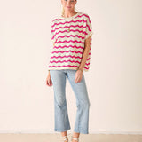 Woman wearing a pink and white striped shirt with light blue jeans on a plain background