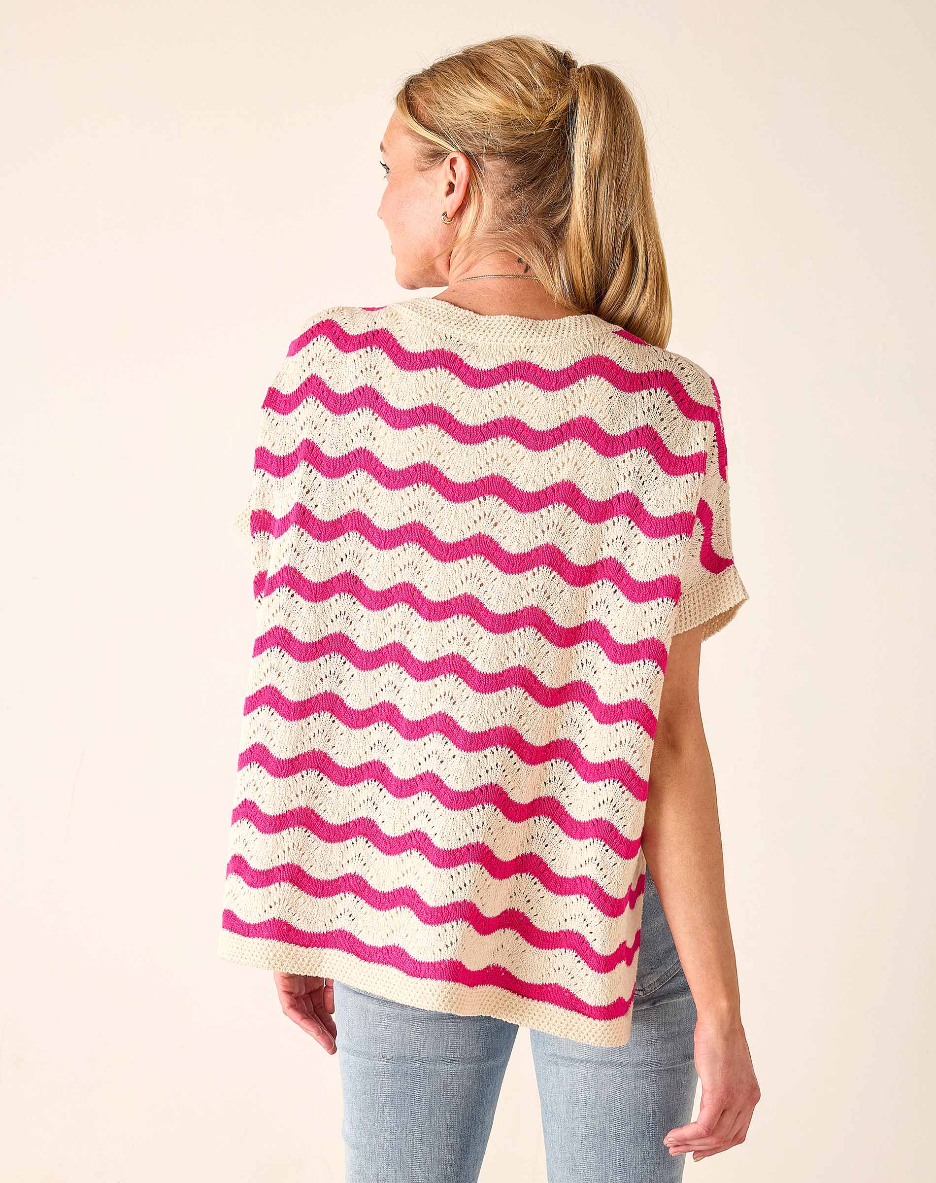 Woman wearing a pink and white striped poncho against a beige background
