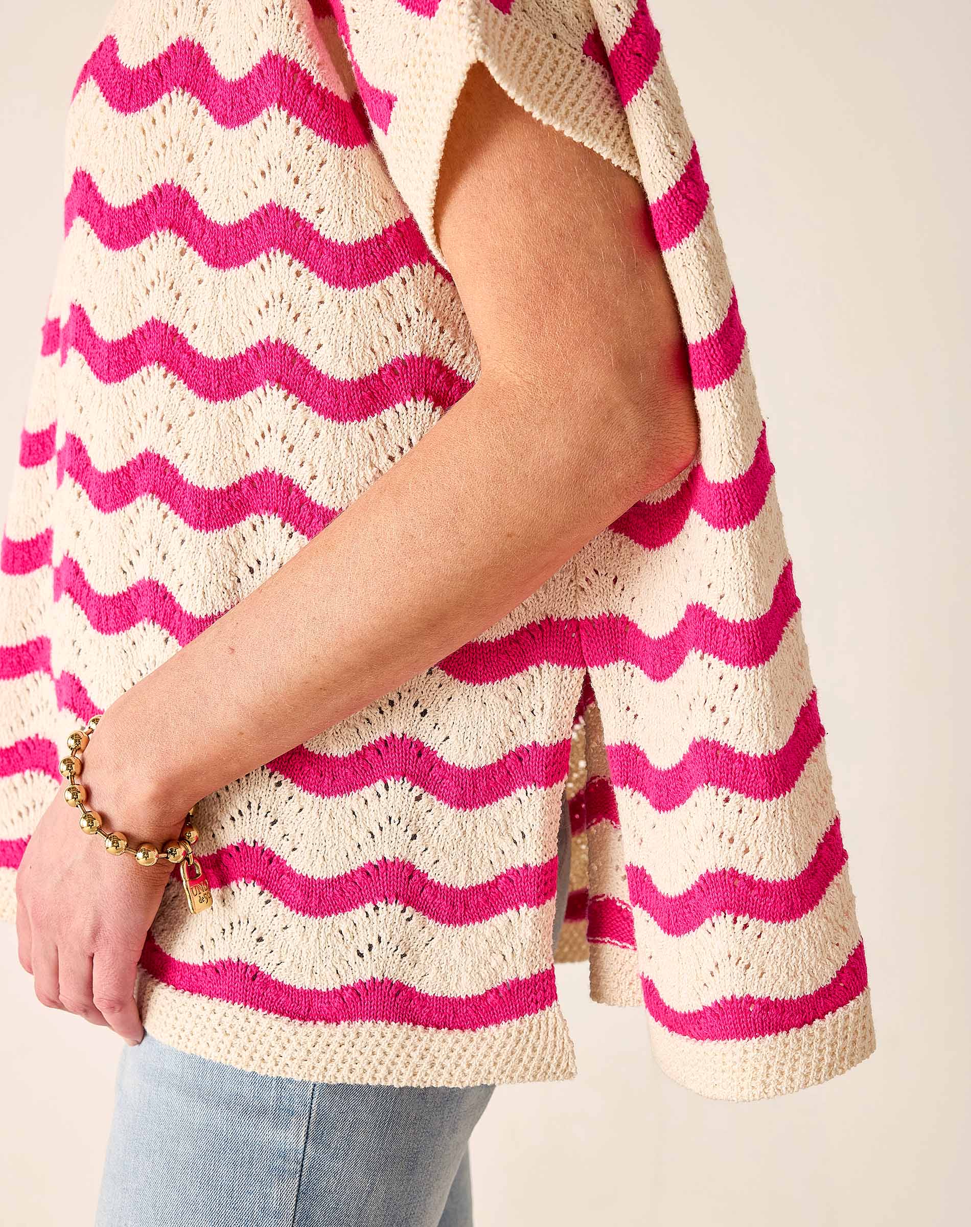 Person wearing a pink and white striped sweater with a plain background