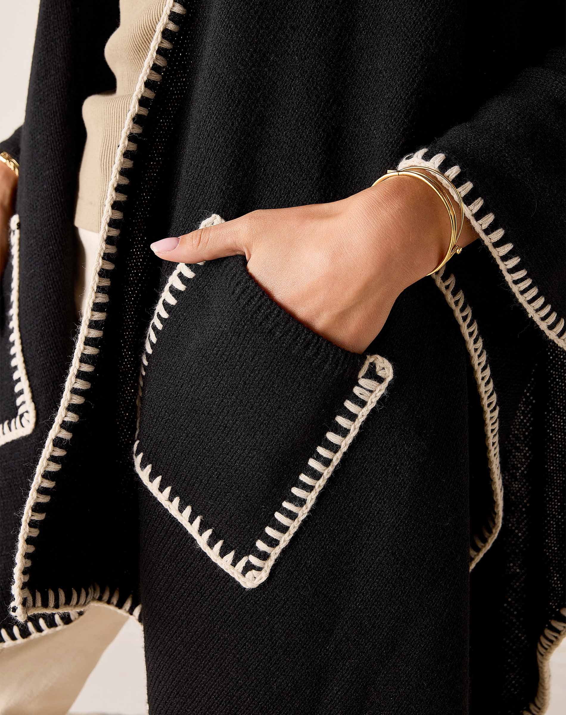 Close-up of the cream and black whipped stitch detail on a knit travel wrap.