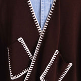 MERSEA ladies' travel-ready women's travel-friendly detail view of the chocolate brown knit wrap featuring a white whipstitch edge and front pockets.