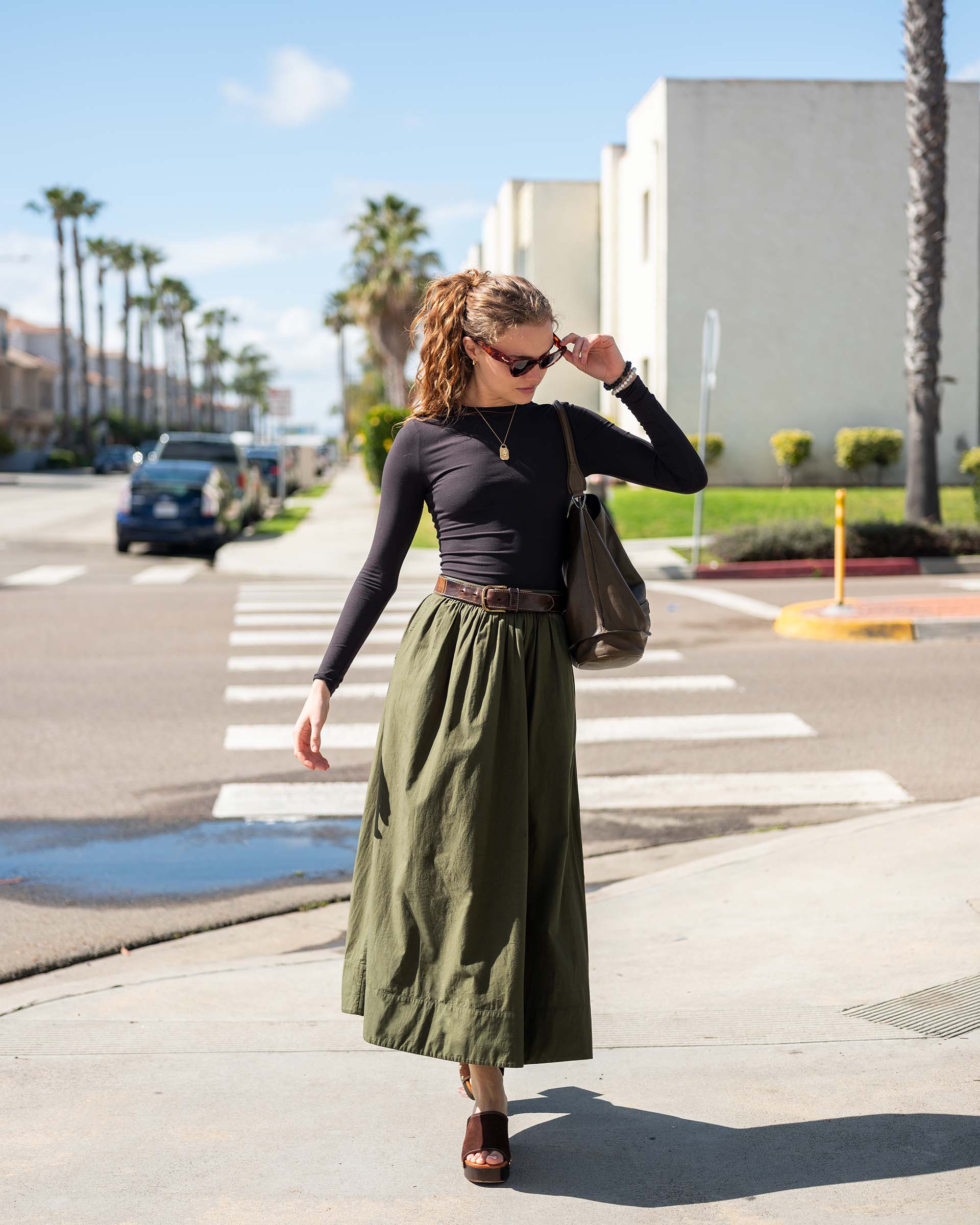 MERSEA ladies' travel-ready forest green maxi skirt with a gathered waist and wide hem in an outdoor coastal setting.