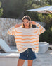 Womens White and Orange Striped Midweight Sweater Standing Travel Destination Look Hands on Head