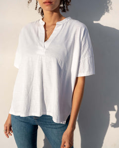 Person wearing a white shirt and blue jeans against a plain background