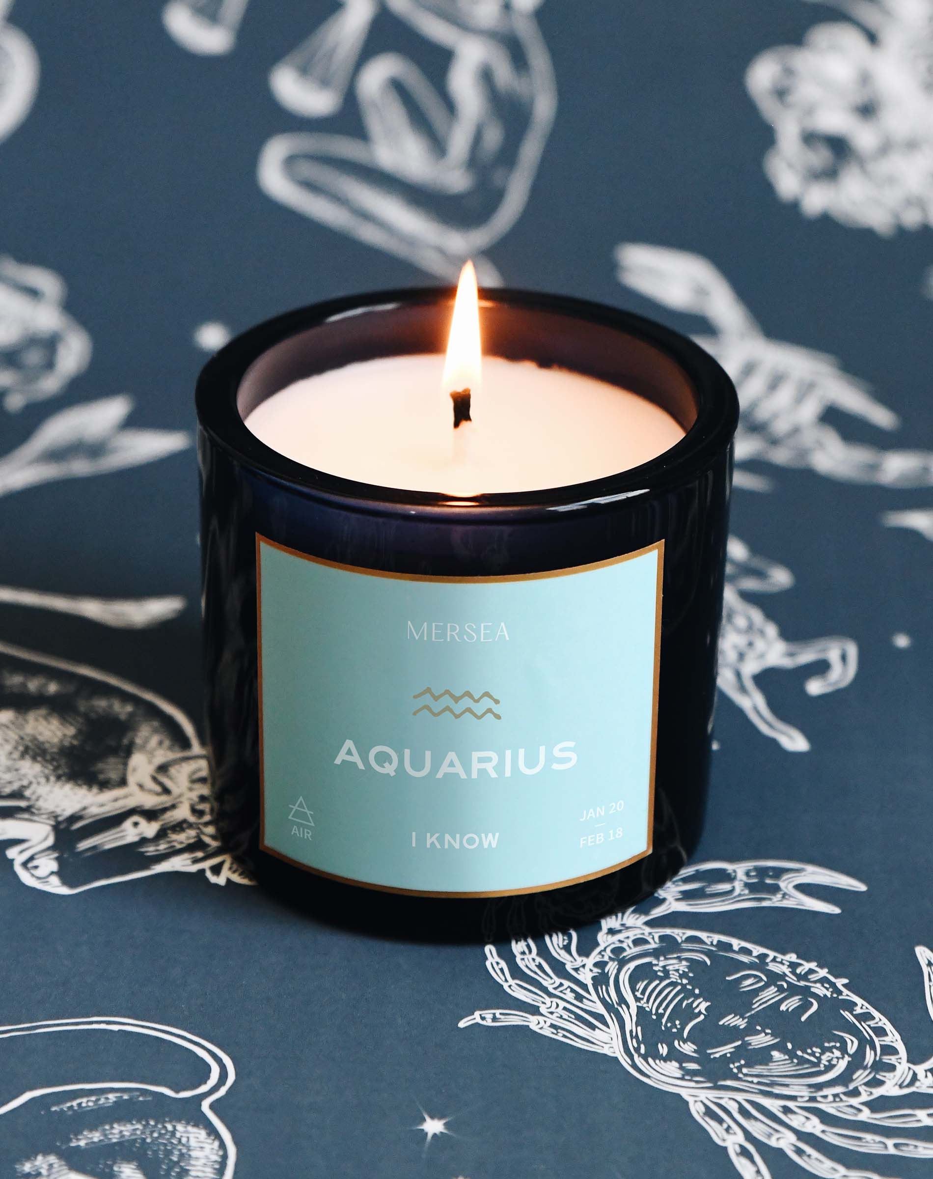 Candle labeled 'Aquarius' with a blue label on a dark blue background with zodiac signs.