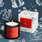 Aries candle and packaging on a zodiac-themed background