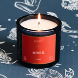 Candle with 'Mersea' label on a dark background with zodiac designs
