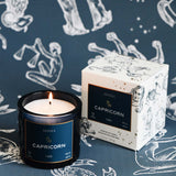 Capricorn candle and packaging on a dark blue background with astrological designs