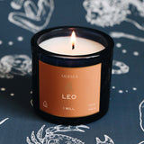 Candle with a 'Mersea' label on a dark background with astrological designs