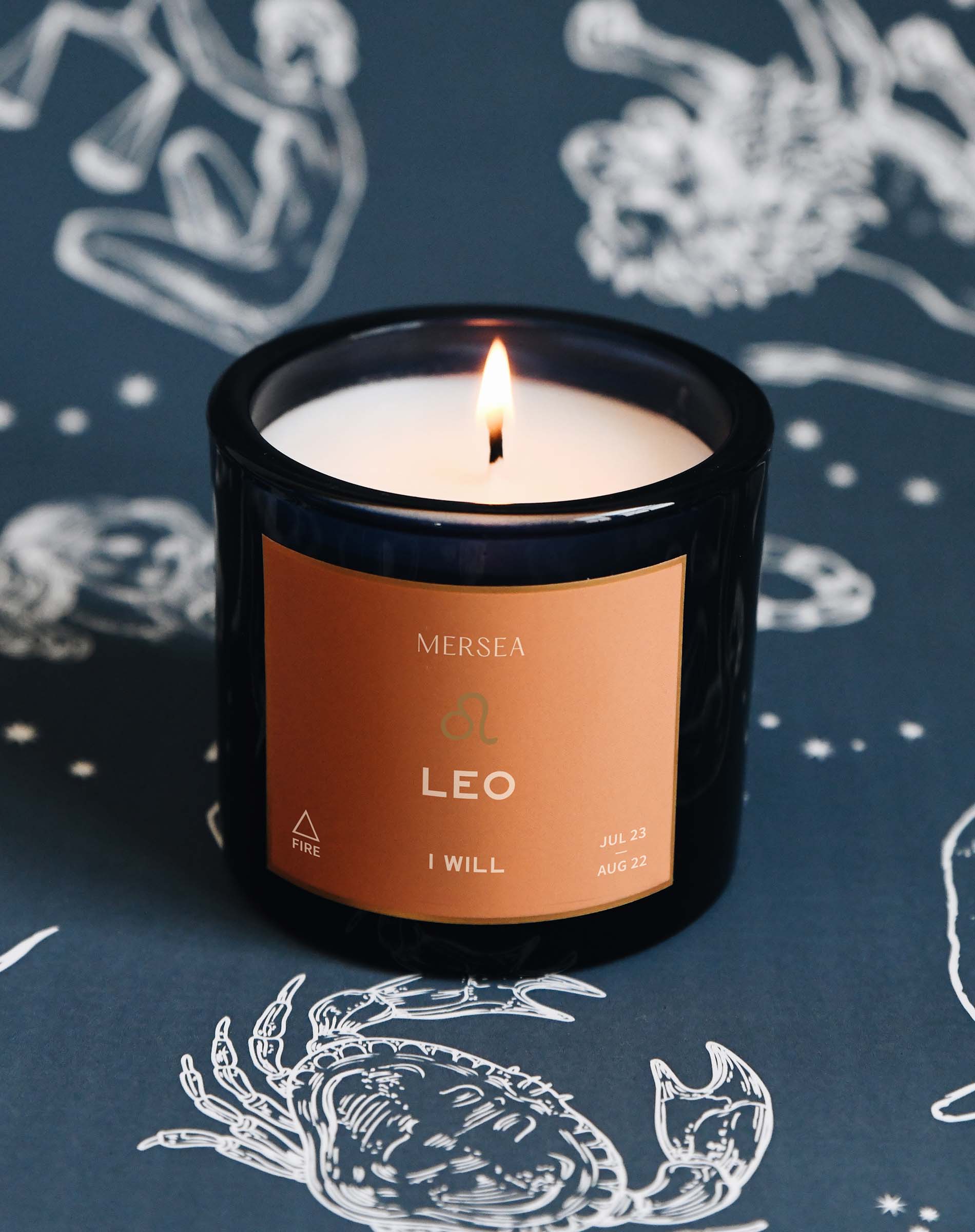 Candle with a 'Mersea' label on a dark background with astrological designs