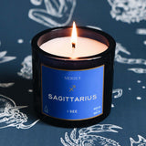 Scented candle labeled 'Sagittarius' by Mersea on a dark background with zodiac designs.