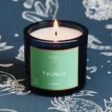 Candle with a 'Mersea' label on a blue background with zodiac designs