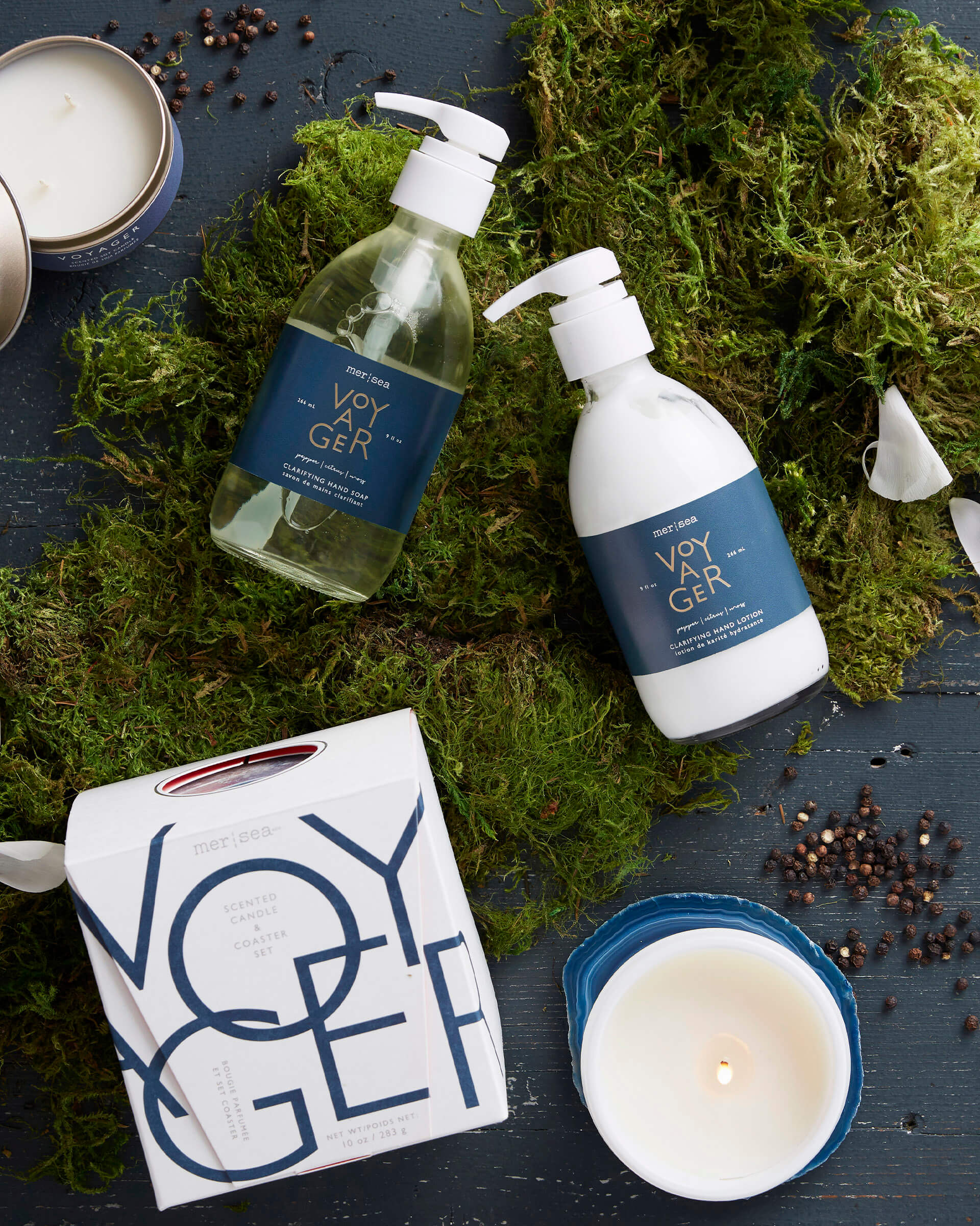 voyager liquid hand soap shea lotion and boxed candle laying on grass
