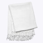 white hand-dyed shibori blanket with fringe folded up on a white backgroundwhite hand-dyed shibori blanket with fringe folded up on a white background