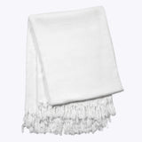 white hand-dyed shibori blanket with fringe folded up on a white backgroundwhite hand-dyed shibori blanket with fringe folded up on a white background