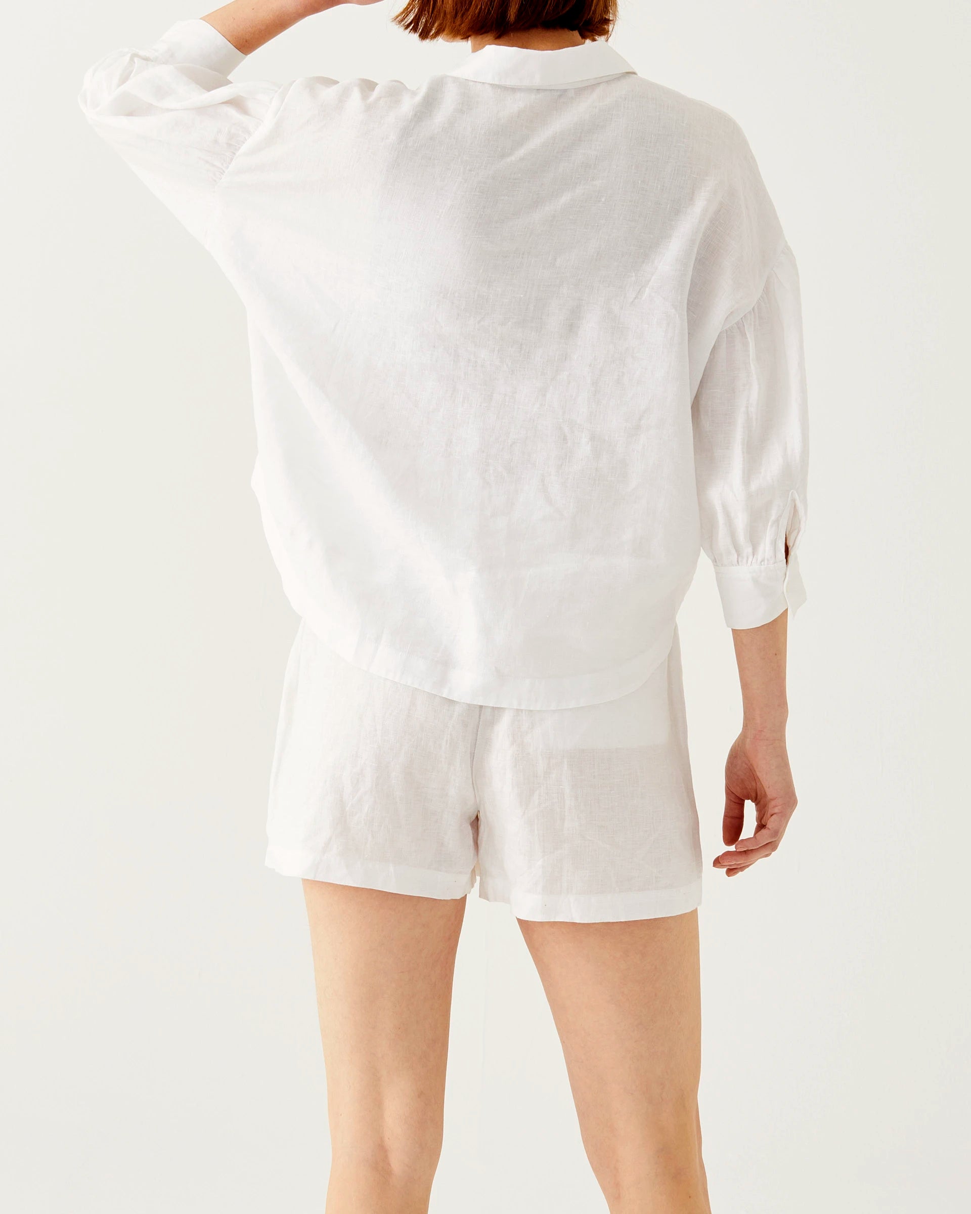 female wearing white linen shorts with belt and matching top backwards on a white background