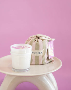 6.5 oz coconut sugar sandbag candle in pink and neutral striped bag on a pink background