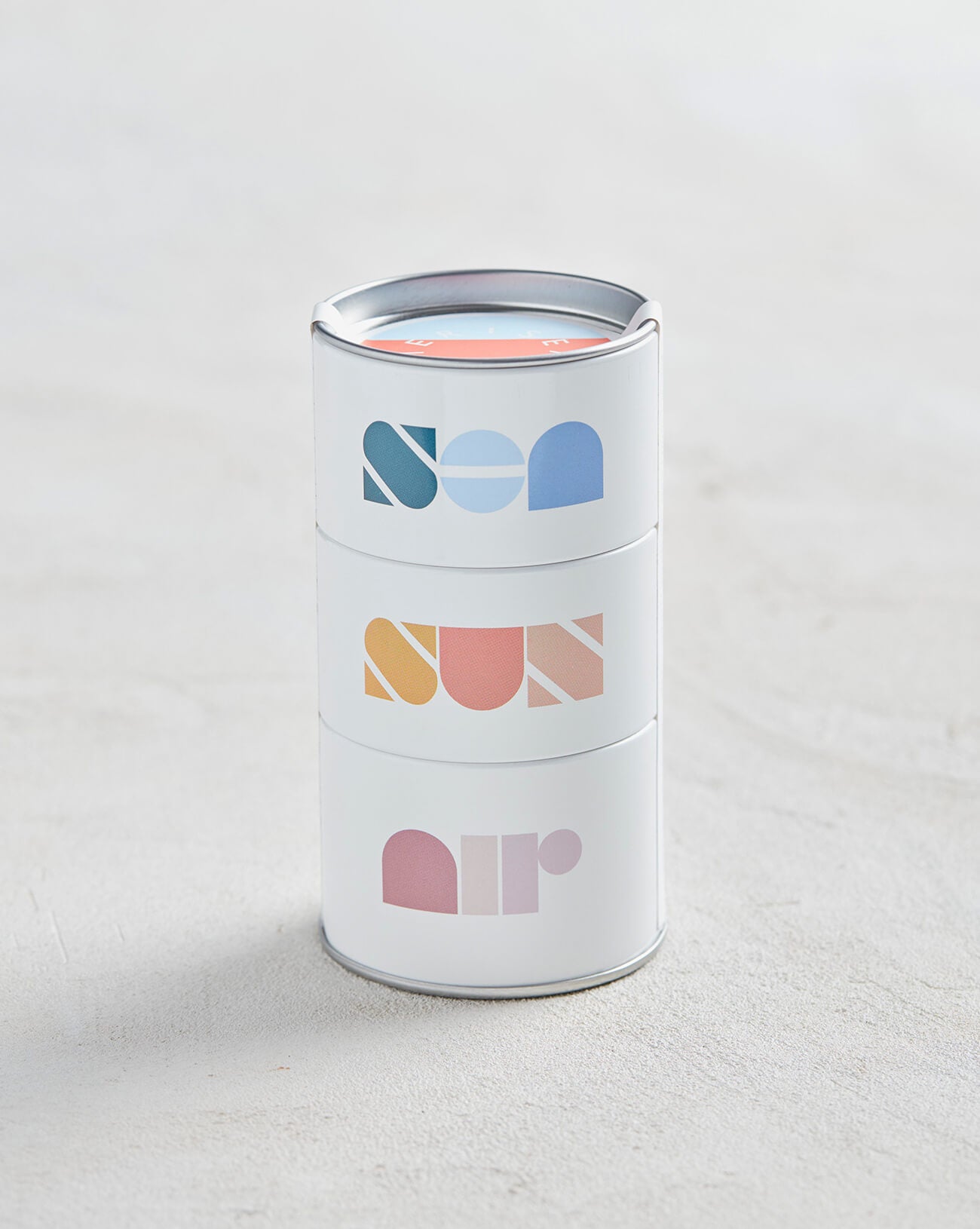 stack of three candles with sea sun and air written on them sitting on a white background