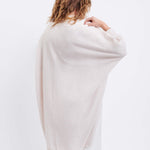 female wearing off white kimono sweater standing backwards on a white background