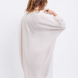 female wearing off white kimono sweater standing backwards on a white background