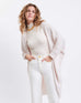 female wearing off white kimono sweater with both hands in her pocket on a white background