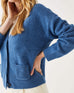 close up of female wearing denim blue buttoned cardigan with patch pockets on a white background