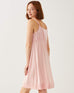 female wearing light pink satin pajama sleep dress looking over a shoulder on a white background
