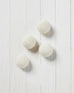 several white wool dryer balls laying on a white wood background