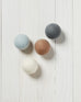 white, brown, grey and dark grey wool dryer balls laying on a white wood background