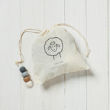 white draw string bag with brown, grey and white wool dryer balls inside on a white background 